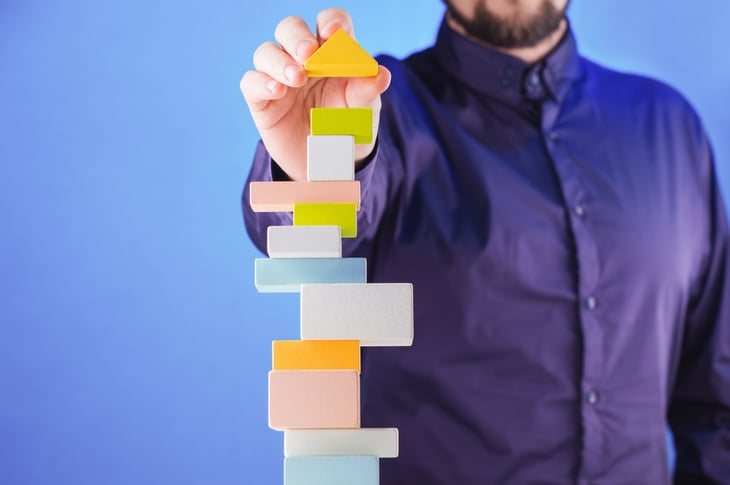 Uomo_compone_torre_blocchi_colorati